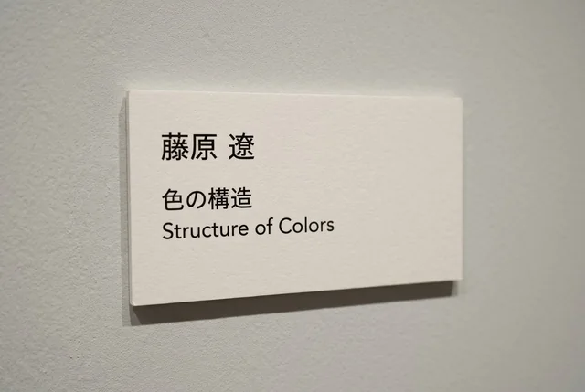 キャプション（説明札）のアップ。作家名「藤原 遼」、作品名「色の構造」、英題「Structure of Colors」が書かれている